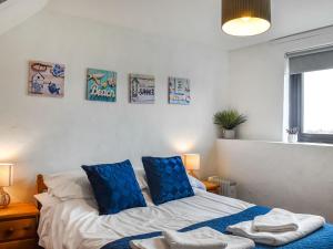ein Schlafzimmer mit einem Bett mit blauen Kissen in der Unterkunft Dizzard Cottage in Bude