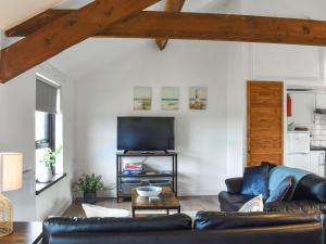 ein Wohnzimmer mit Sofa und Fernseher in der Unterkunft Dizzard Cottage in Bude