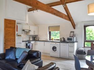 ein Wohnzimmer mit Couch und Küche in der Unterkunft Dizzard Cottage in Bude