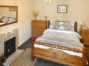 ein Schlafzimmer mit einem Holzbett und einem Kamin in der Unterkunft Professors Cottage in Girvan