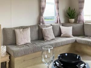 a living room with a gray couch and a wine glass at Farne Lodge in Berwick-Upon-Tweed