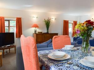 ein Esszimmer mit Tisch und Stühlen und einem Fernseher in der Unterkunft Forge Masters Cottage in Middlewich