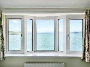 ein Fenster mit vier Ausblicken auf das Wasser in der Unterkunft Lantreath in Saint Mawes