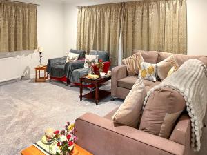 a living room with two couches and a table at Woodside Cottage in Pinwherry