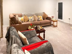 a living room with two couches and a table at Woodside Cottage in Pinwherry