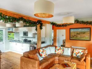 sala de estar con sofá marrón y cocina en Church Park, en Okehampton