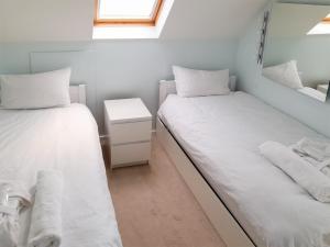 two beds in a room with white sheets and pillows at Gorsehill House in Poole