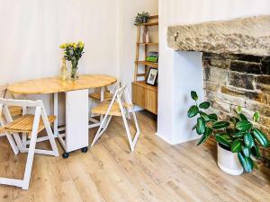 a table and chairs in a room with a fireplace at Saltaire Mill Cottage in Saltaire