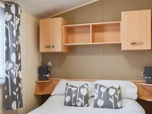 a bedroom with a bed and wooden cabinets at Stay And Sea in Heysham