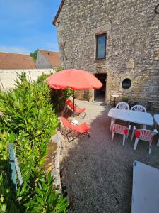 a patio with a table and chairs and an umbrella at Les gardiens d'antan in Béru