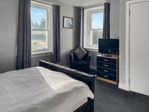 Un dormitorio con una cama y una silla y un televisor. en Fleet Townhouse, en Gatehouse of Fleet