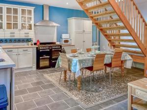 a kitchen with a table with chairs and a staircase at Court Place in Misterton