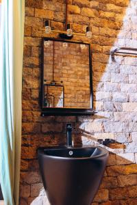 a bathroom with a black sink and a brick wall at Ibuye Villa Holiday Home in Nyakinama