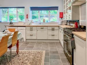 a kitchen with white cabinets and a table with a dining room at Court Place in Misterton