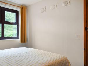 a white bedroom with a bed and a window at Hey Ho Cottage in Whitby