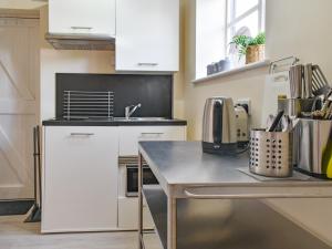 a kitchen with white cabinets and a counter top at Rookmead Cottage in Yarmouth