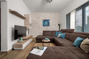 a living room with a brown couch and a flat screen tv at Wunderschöner Neubau Bungalow Mit Privatem Pool Und Jacuzzi in Vozilići