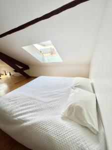 a bedroom with a white bed with a skylight at Maison Blanc de blanc - Guest Room in a Family Home in Le Mesnil-sur-Oger
