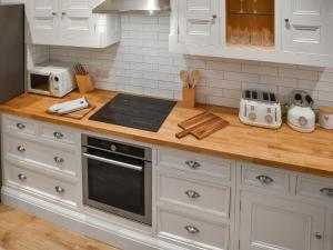 a kitchen with white cabinets and a stove top oven at Norfolk Headquarters in Fakenham