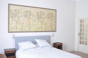 a bedroom with a bed with a painting on the wall at Relais des Vignerons, Chambres d'hôtes in Conilhac-Corbières