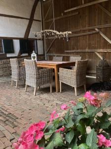 a wooden table with four chairs and pink flowers at boerderij, voorhuis in Schimmert +12 photos