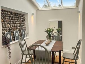 una sala da pranzo con tavolo, sedie e soffitto in vetro di Samphire Cottage a Cromer