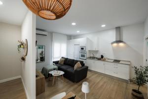 a living room with a couch and a kitchen at Apartamentos LUXURY SUITES MACABEO in Almendralejo