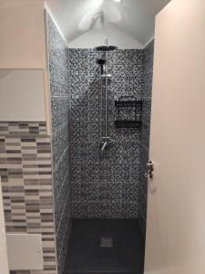 a bathroom with a shower with a black and gray tiles at MM House in Bicas
