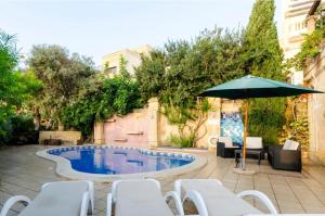 a patio with a pool and an umbrella and chairs at Il-Wileg B&B in Qala