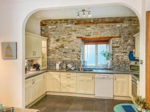 a kitchen with white cabinets and a stone wall at The Nest in Llandeilo