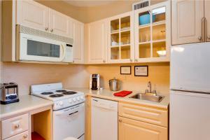a kitchen with a stove, microwave, sink and refrigerator at Sun Harbour Boutique Hotel in Miami Beach