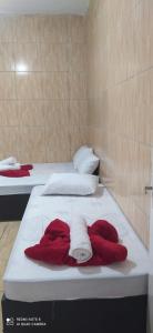 two beds with red and white towels on them at Pousada Flat do Igor com Ar Condicionado Perto da Basílica de Aparecida com 1 vaga Gratuita no Estacionamento in Aparecida