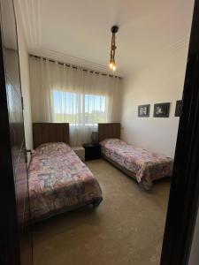a room with two beds and a window at Les perles de tamaris dar bouazza in Dar Mohammed Ould Haj Jilali