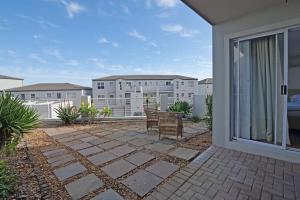 un patio con un banco en el balcón en Modern Coastal Condo in Big Bay, en Cape Town