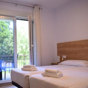 two beds in a hotel room with towels on them at Villa El Encinar de Noja in Noja