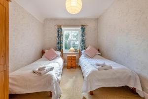 twee eenpersoonsbedden in een kamer met een raam bij Stone Cottage - Swanage in Swanage