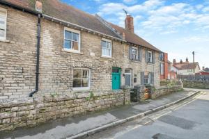 een stenen huis met een groene deur in een straat bij Stone Cottage - Swanage in Swanage