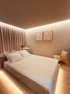 a bedroom with a large white bed and a chair at Casa de Agrelos Country House in Penafiel +63 photos