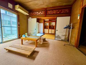 名古屋楽旅人的一间带客厅的房间，配有一张桌子；另一间带床的房间