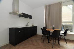a kitchen with black cabinets and a table with chairs at Modern apartment nearby Eindhoven in Leende +6 photos