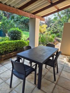une table noire et des chaises sur une terrasse dans l'établissement Ulu Garden Cottage, à Ramsgate