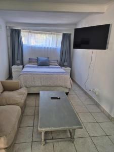 une chambre avec un lit, un canapé et une télévision dans l'établissement Ulu Garden Cottage, à Ramsgate