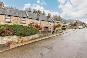 an old stone house on a street in a village at Lion Cottage in Stanton in Peak