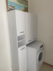 a white laundry room with a washing machine and a cabinet at Falegnameria del Conte in Montecorice