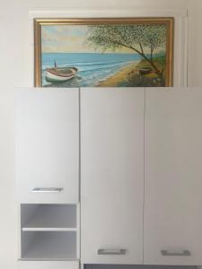 a painting of a boat on top of a white cabinet at Falegnameria del Conte in Montecorice