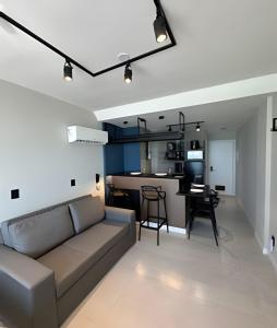 Una sala de estar con un sofá y una cocina. en Loft Refugio Azul - 307, en Arraial do Cabo