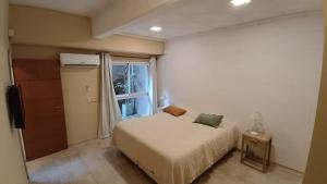 een kleine slaapkamer met een bed en een raam bij Departamento Divino a tres cuadras de la playa. in Carilo