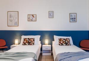 Dos camas en una habitación con azul y blanco. en Skyline Ottavo Cielo, en Módena