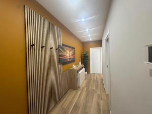 a hallway with a bathroom with yellow walls and wooden floors at EtnalanHOME in Misterbianco