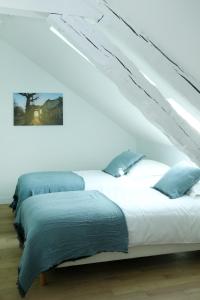 two beds with blue pillows in a white room at La Petite Fontaine in Senlis